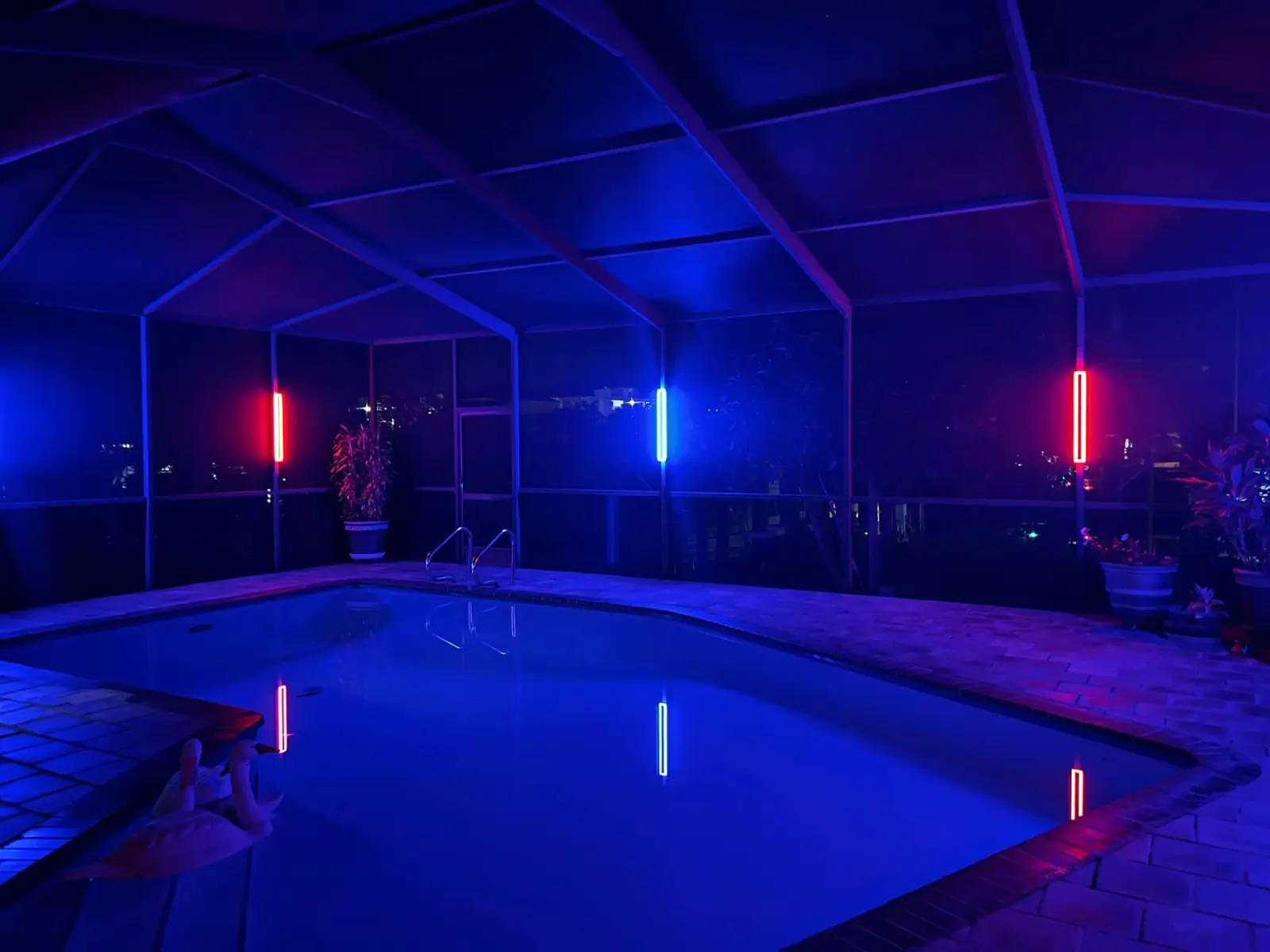 The same Zuzack pool cage lit deep blue, with red accent bars