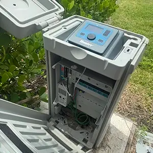 Smart irrigation controller box open on a wall, showing its wiring